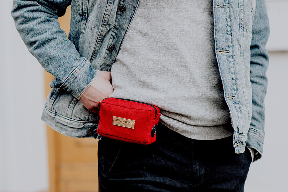 A man wearing a Bowl&Bone Republic denim jacket holding a Bowl&Bone Republic red dog treat bag.