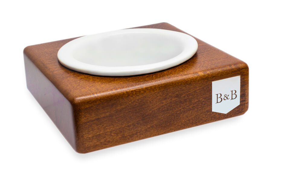 A wooden box with a dog bowl SOLO CERAMIC amber by Bowlandbone on top.