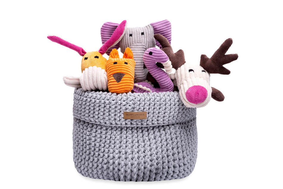 A Bowlandbone grey knitted basket filled with stuffed animals.