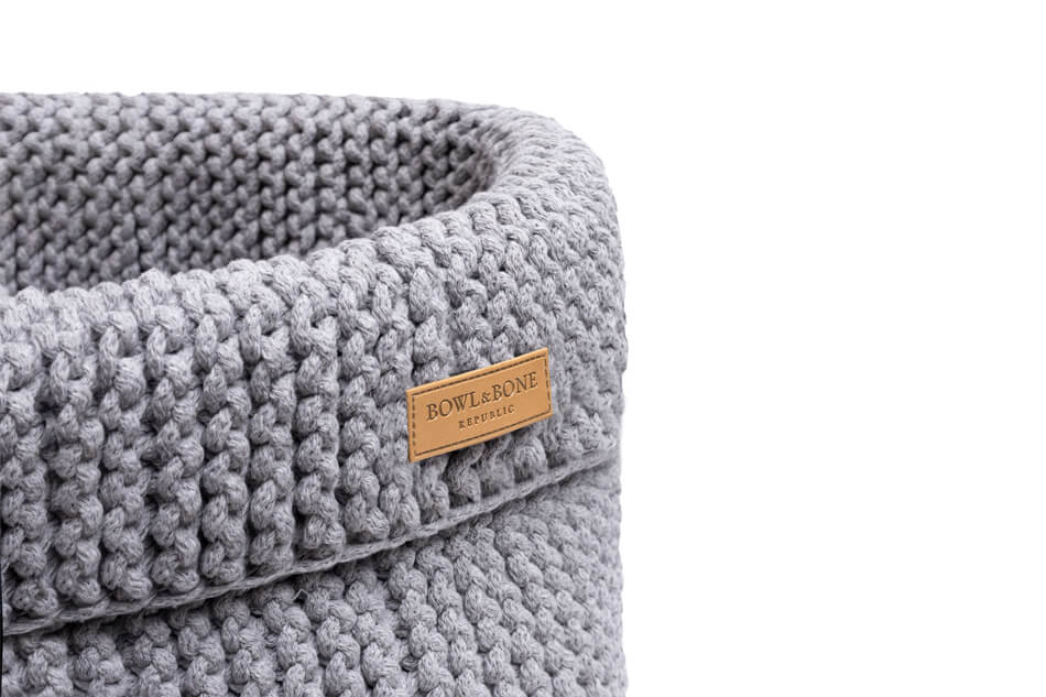 A Bowlandbone grey knitted basket for dog toys COTTON with a label on it.