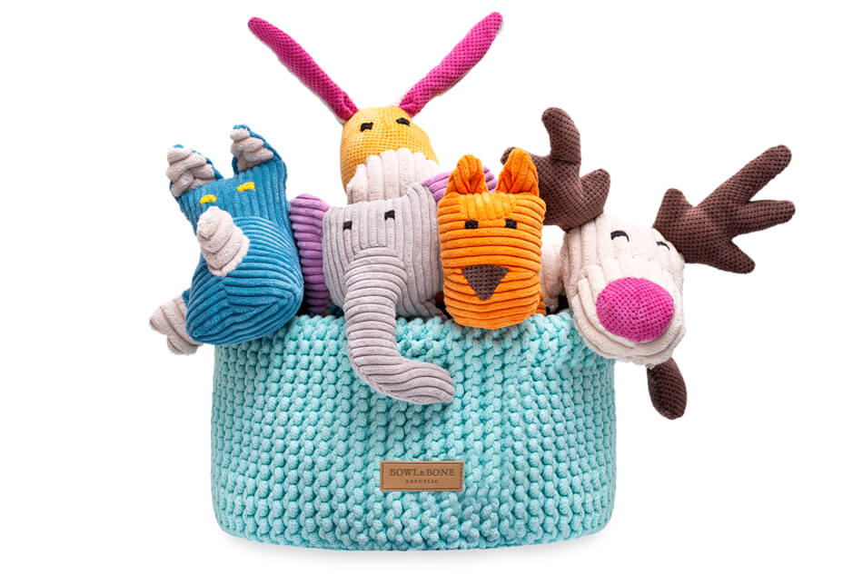 A group of stuffed animals in a double mint blue Bowlandbone basket for dog toys.