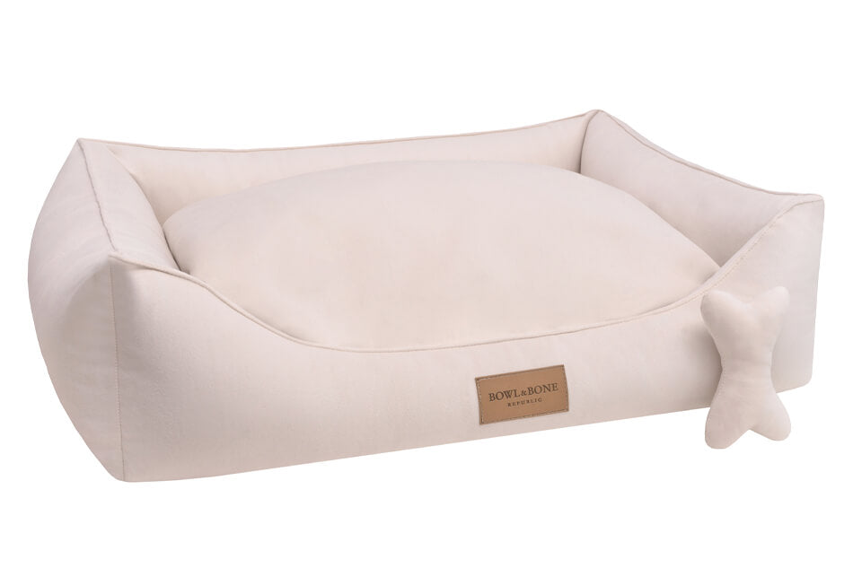 A Bowl&Bone Republic CLASSIC cream dog bed with a bone in it.