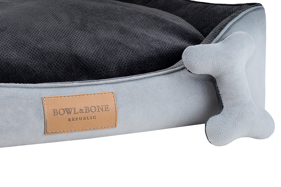 A Bowlandbone dog bed in the CLASSIC grey color featuring a bone motif, designed by Bowl&Bone Republic.