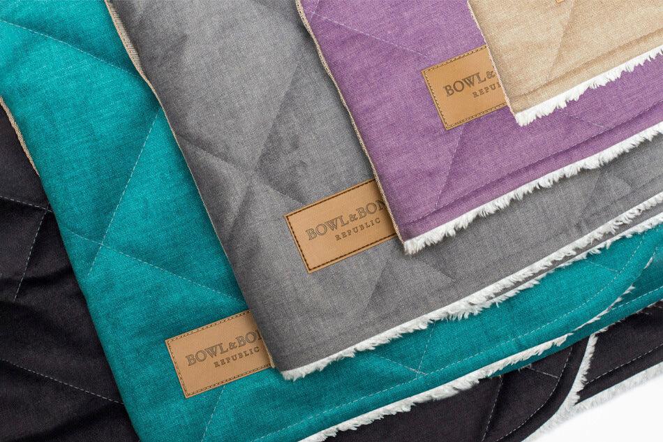 A group of Bowl&Bone Republic quilted blankets in different colors, specifically the dog sleeping bag DREAMY mint.
