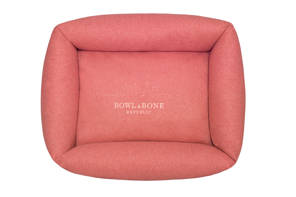 A dog bed with a pink logo by Bowlandbone, featuring the Bowl&Bone Republic.