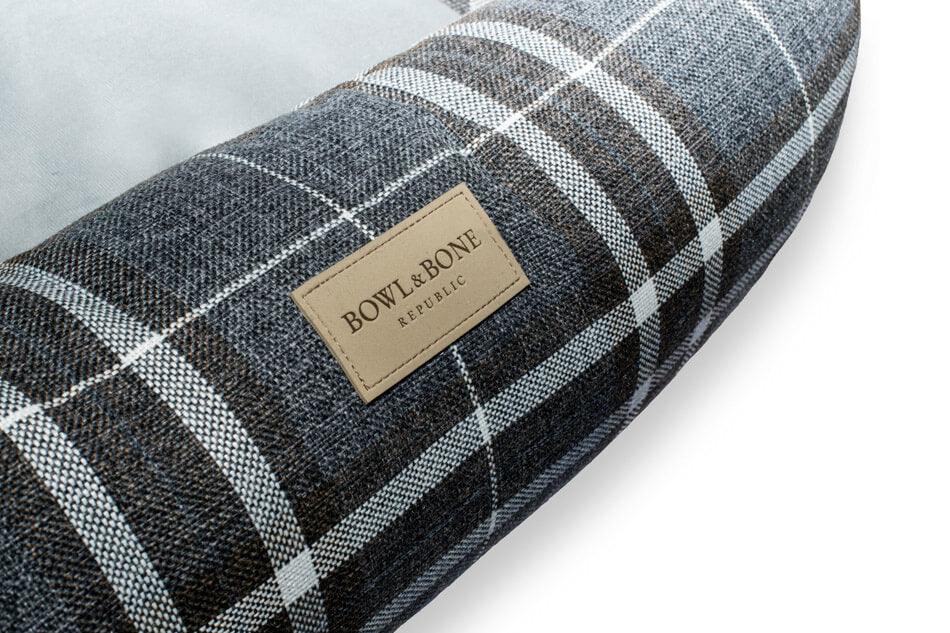 A plaid Bowl&Bone Republic dog bed with a label on it.