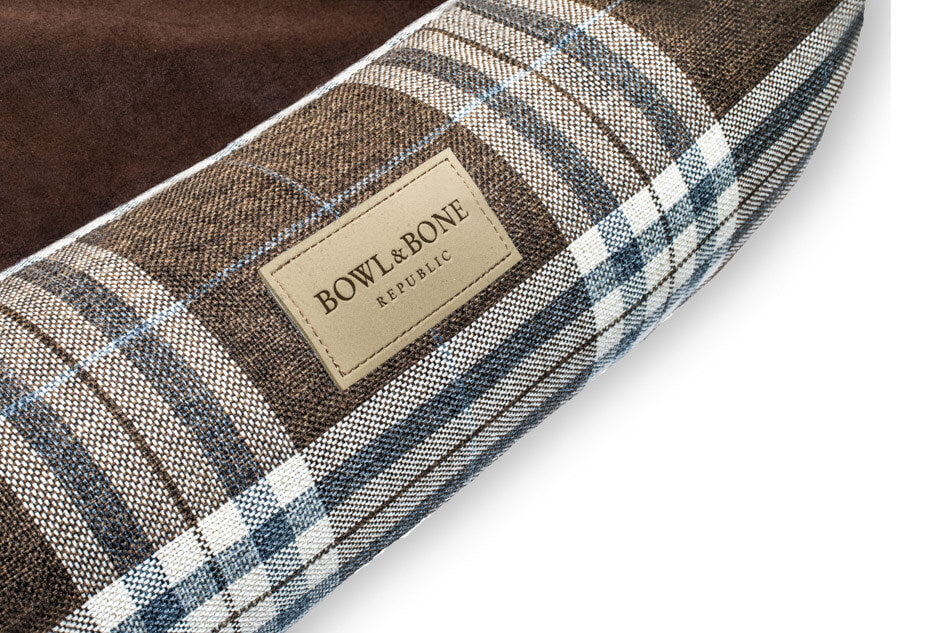 A Brown Bowl&Bone Republic dog bed with a plaid label.
