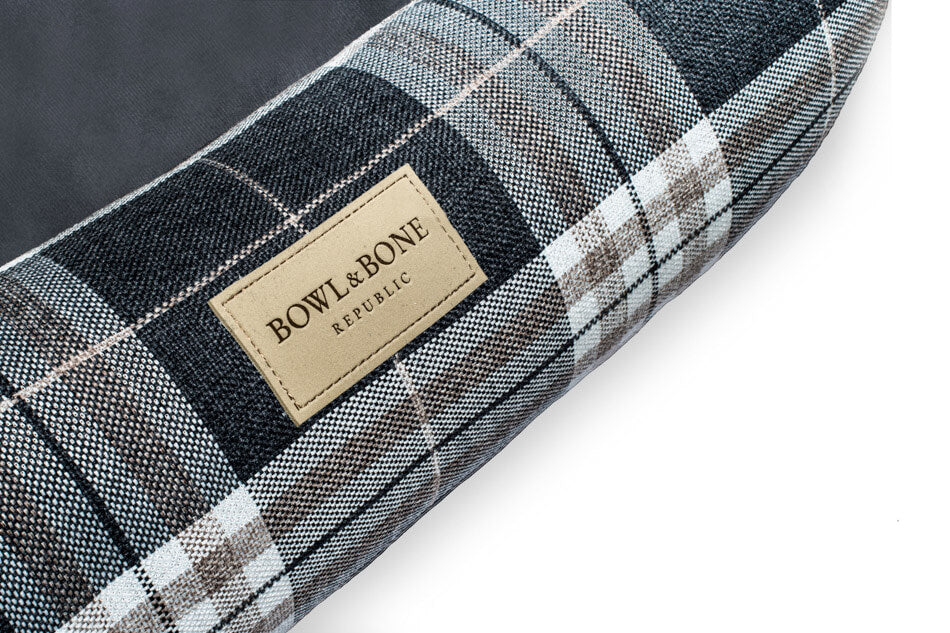 A plaid dog bed SCOTT graphite by Bowl&Bone Republic with a label on it.