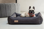 A French Bulldog is sitting in a grey dog bed from Bowl&Bone Republic.
