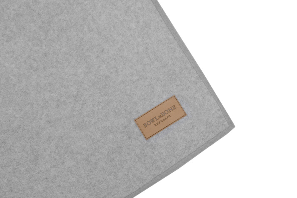 A Zen grey dog blanket made by Bowl&Bone Republic with a brown label on it.