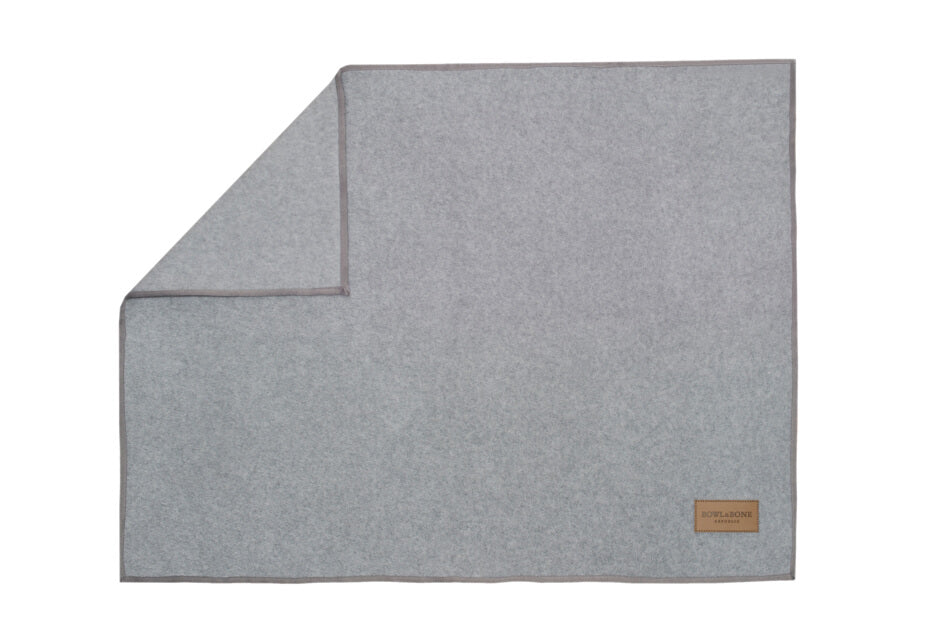 A grey dog blanket by Bowl&Bone Republic with a brown patch.