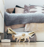 A small Bowl&Bone Republic dog bowl walking in front of a bed.