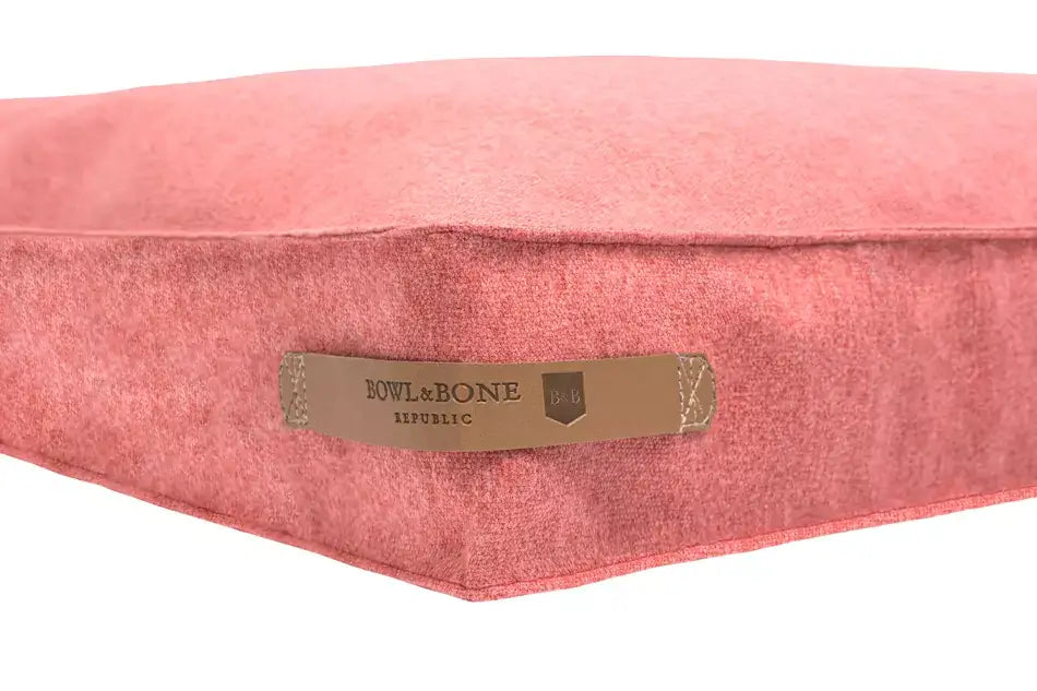 A Bowl&Bone pink dog cushion bed LOFT coral with a label on it.