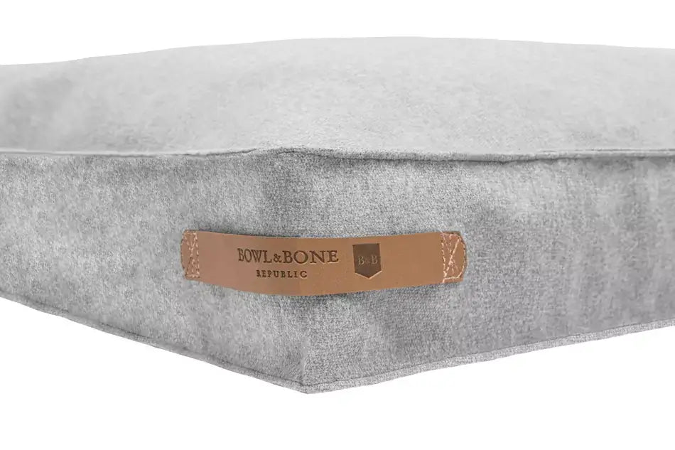 A grey dog cushion bed from Bowl&Bone Republic with a leather label.