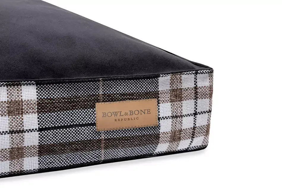 A black and brown plaid dog cushion bed SCOTT graphite on a white background, by Bowl&Bone Republic.