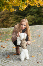 A woman is petting a white Bowl&Bone Republic dog jacket in the autumn.