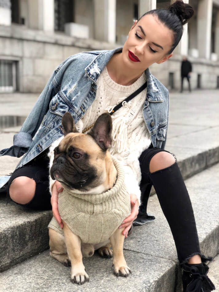 A woman sitting on steps with a Bowlandbone french bulldog in an ASPEN red dog sweater.