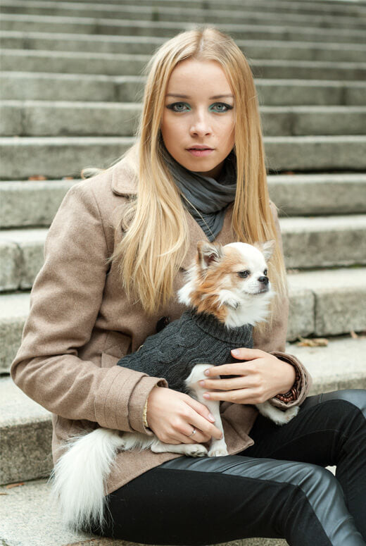 A young woman holding a Bowl&Bone Republic blue ASPEN dog sweater on the steps.