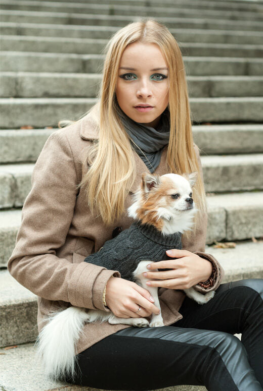 A young woman holding a Bowl&Bone Republic ASPEN navy dog sweater on the steps.