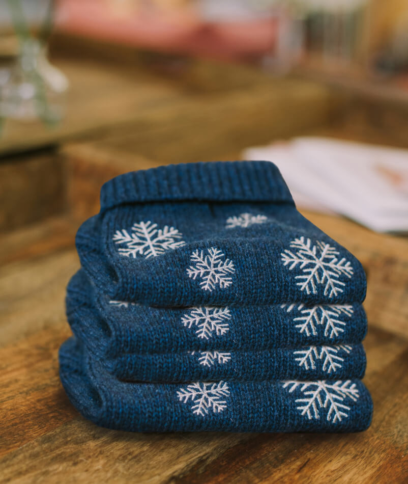 A stack of Bowl&Bone Republic dog sweaters with snowflakes on top.