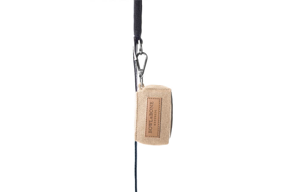 A Bowl&Bone Republic dog waste bag holder MINI beige with a rope attached to it.