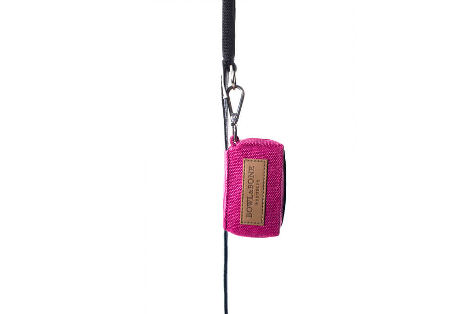 A Bowl&Bone Republic dog waste bag MINI pink holder with a black handle attached to it.